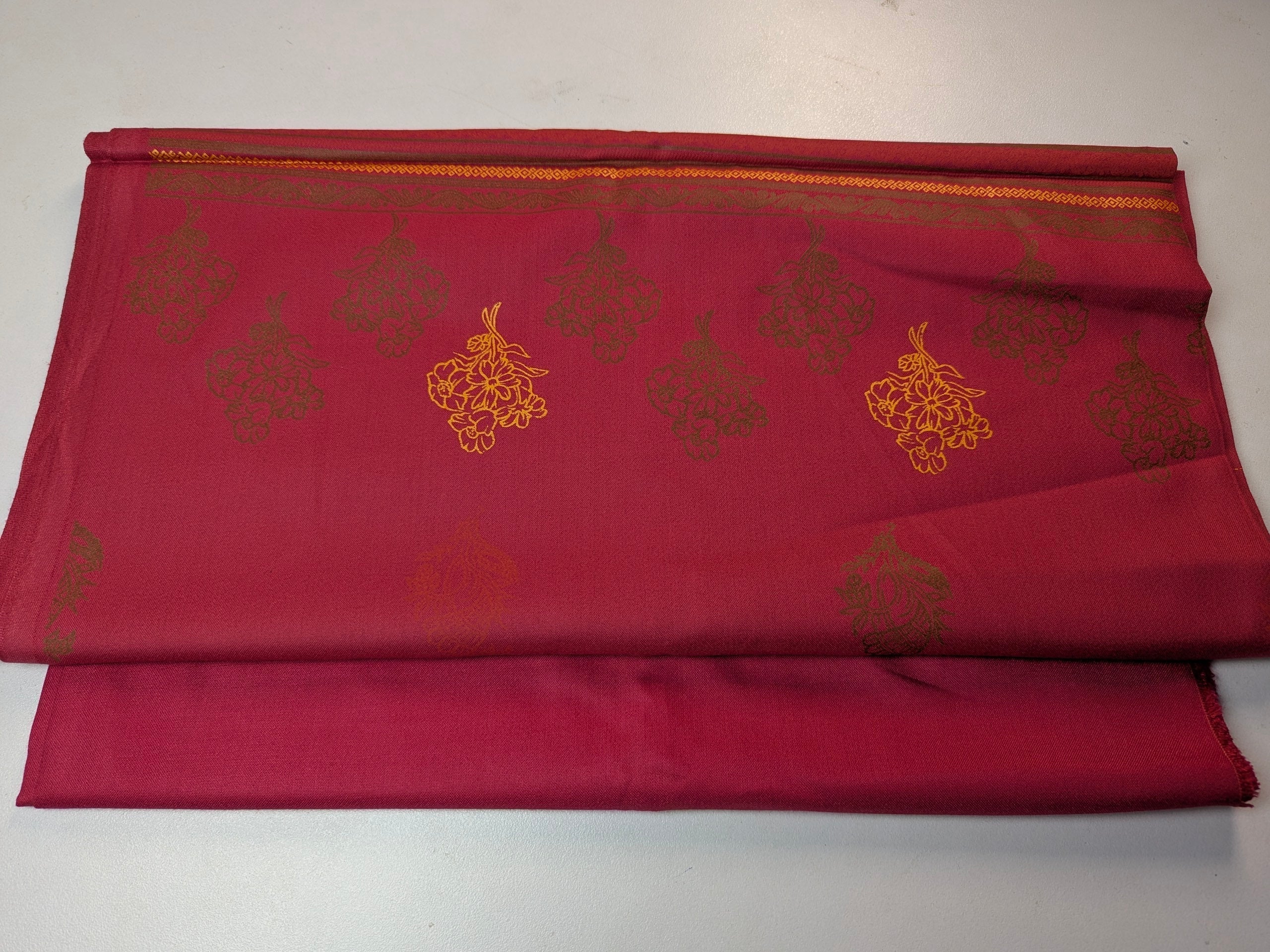 Red fabric with gold embroidery on a white background