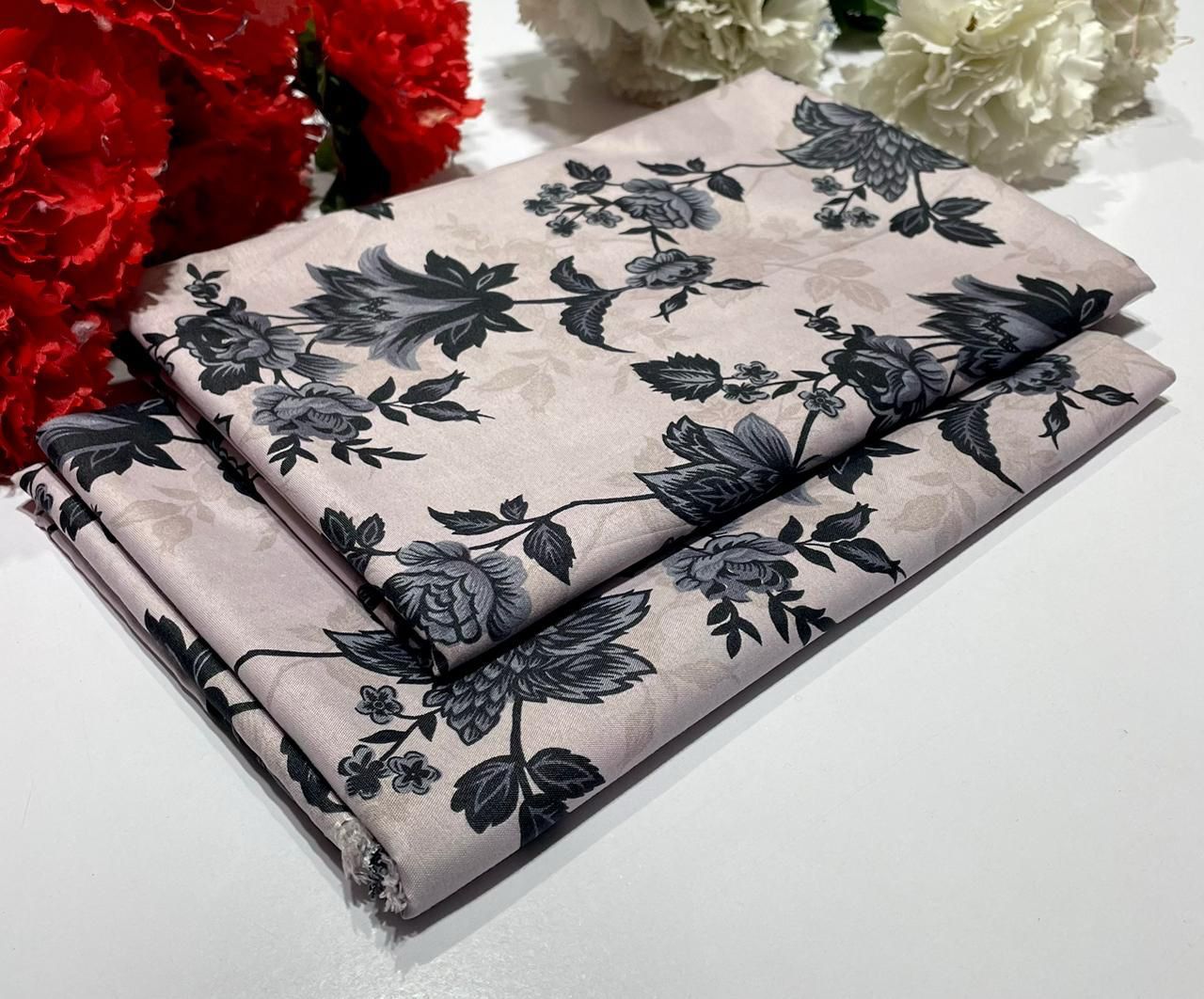 Floral-patterned fabric with black flowers on a beige background, surrounded by red and white flowers.
