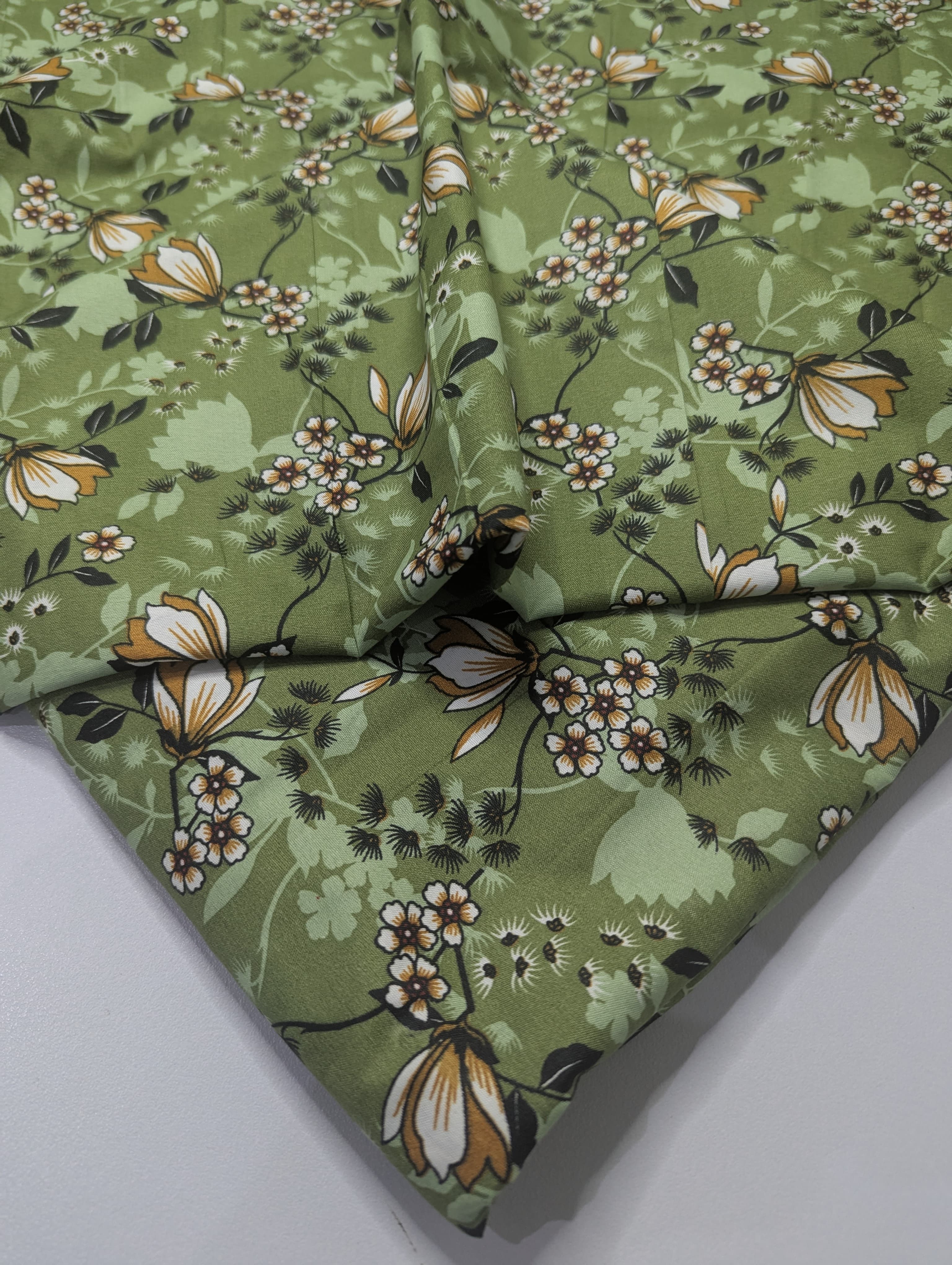 Green floral fabric with a pattern of flowers and leaves on a white background