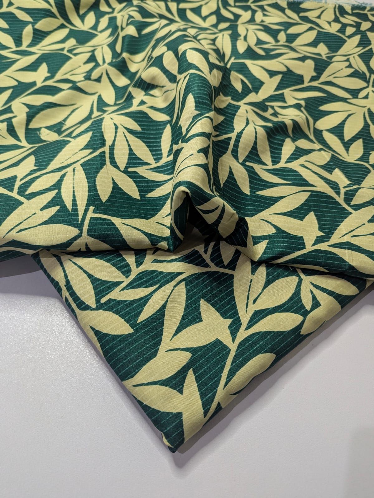 Fabric with green and yellow leaf pattern on a white background