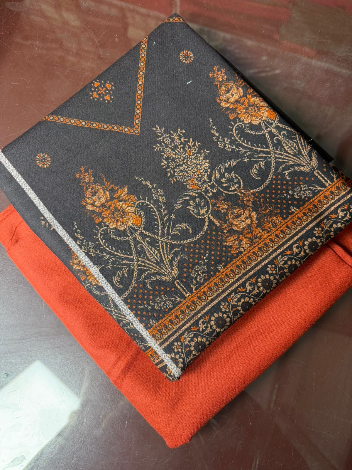 Decorative black fabric with floral patterns on a red surface