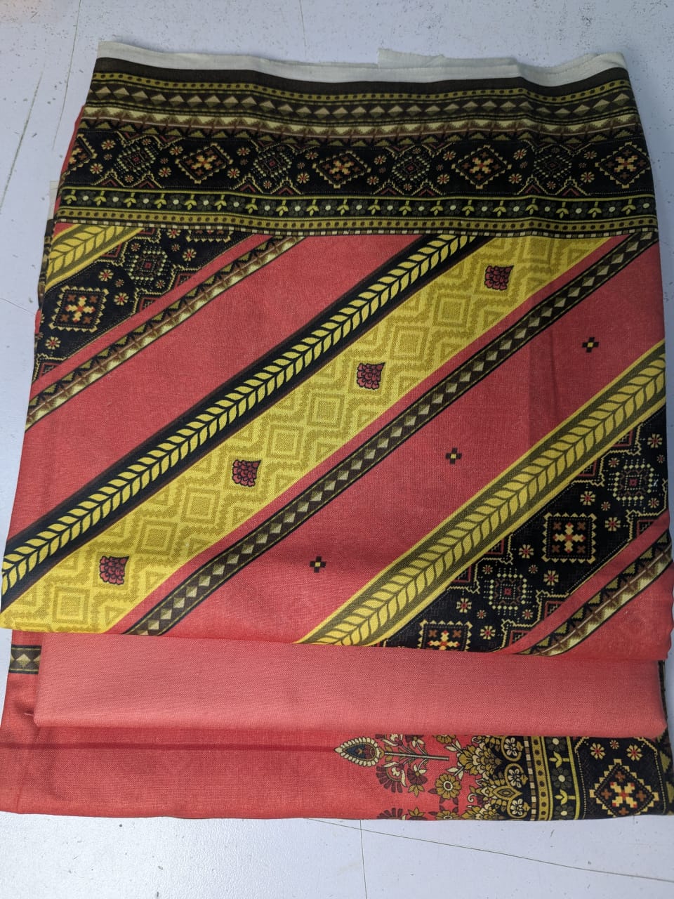 Decorative fabric with red, yellow, and black patterns on a white background