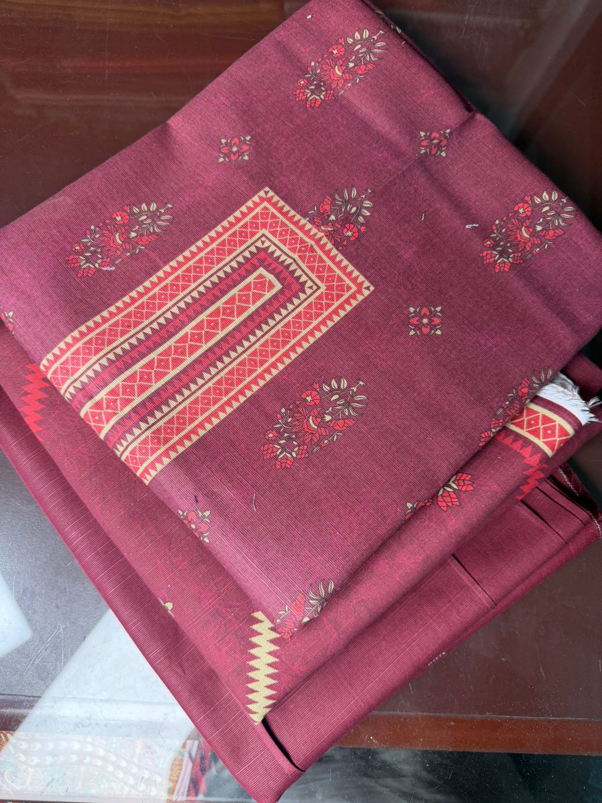 Maroon fabric with intricate patterns on a wooden surface