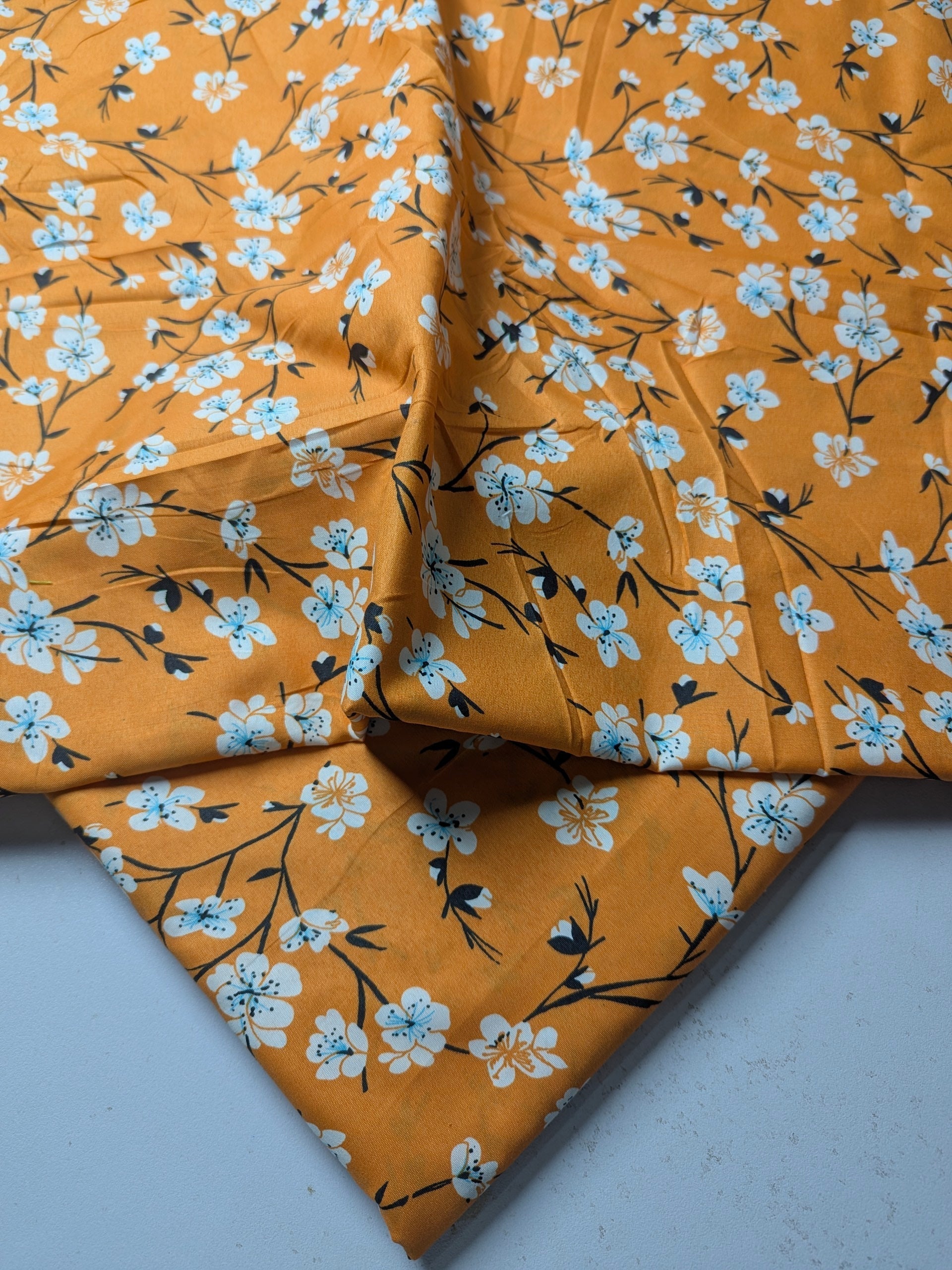 Orange fabric with white floral pattern on a light gray background