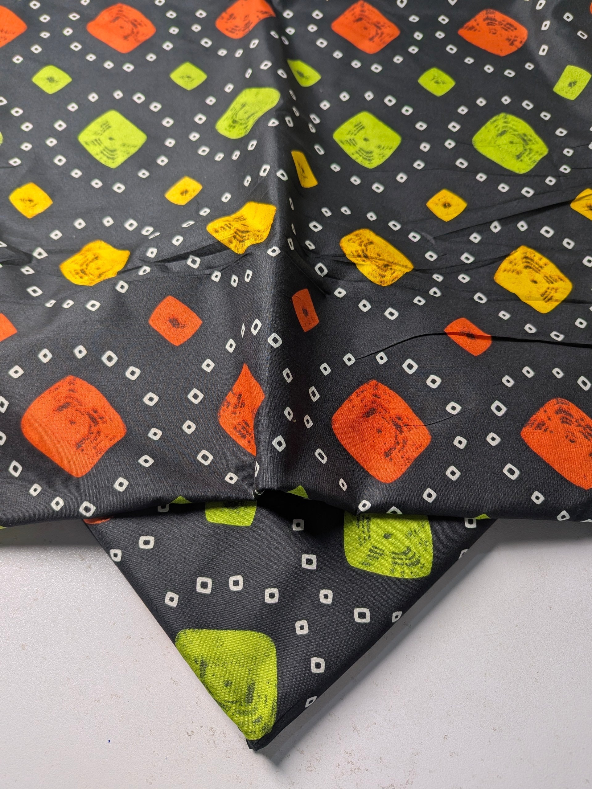 Patterned fabric with orange, green, and yellow shapes on a gray background