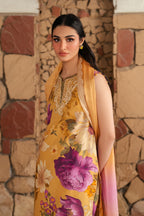 Woman wearing a yellow floral dress with a matching shawl against a stone wall.