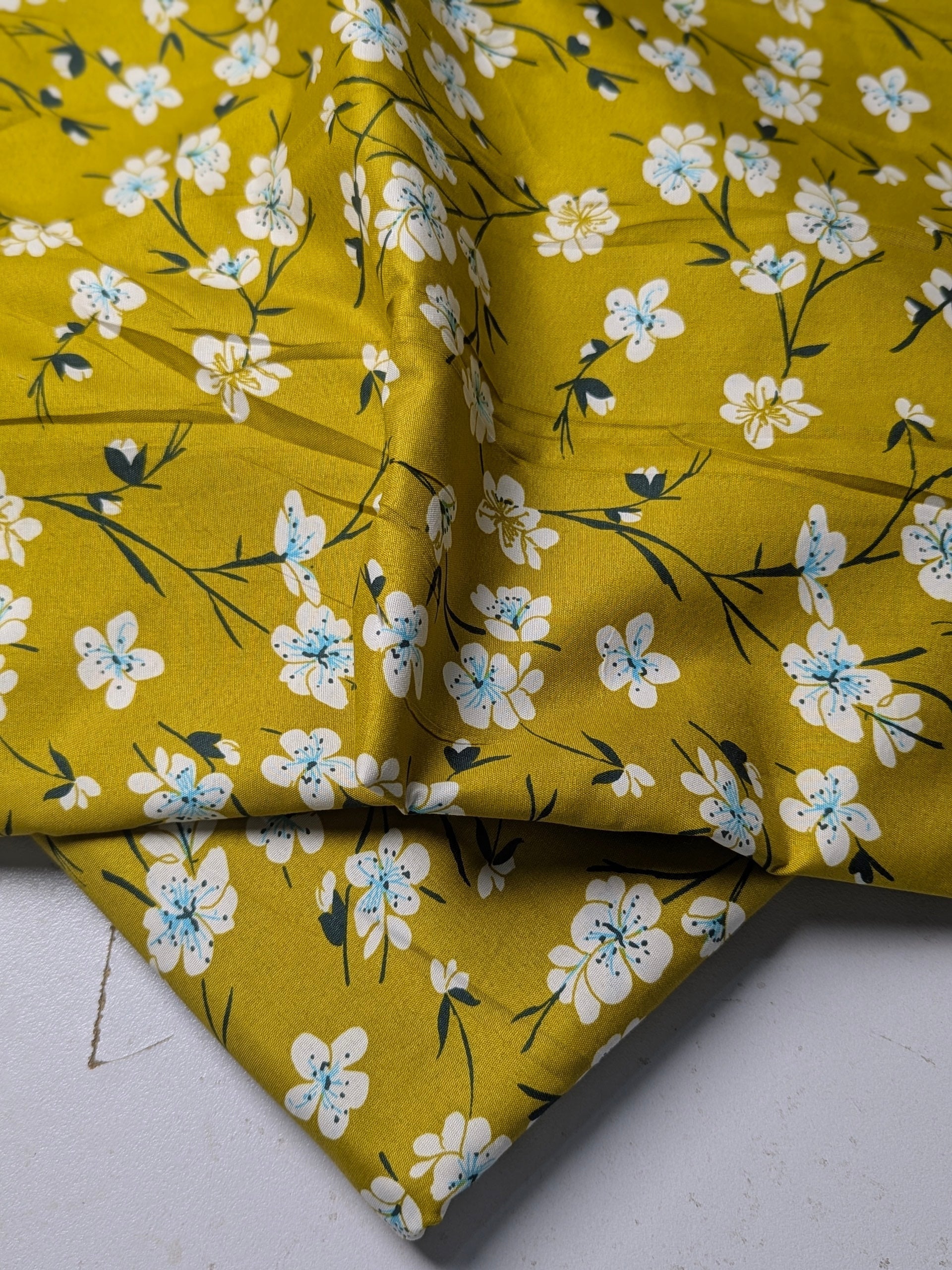 Yellow fabric with white floral pattern on a white background