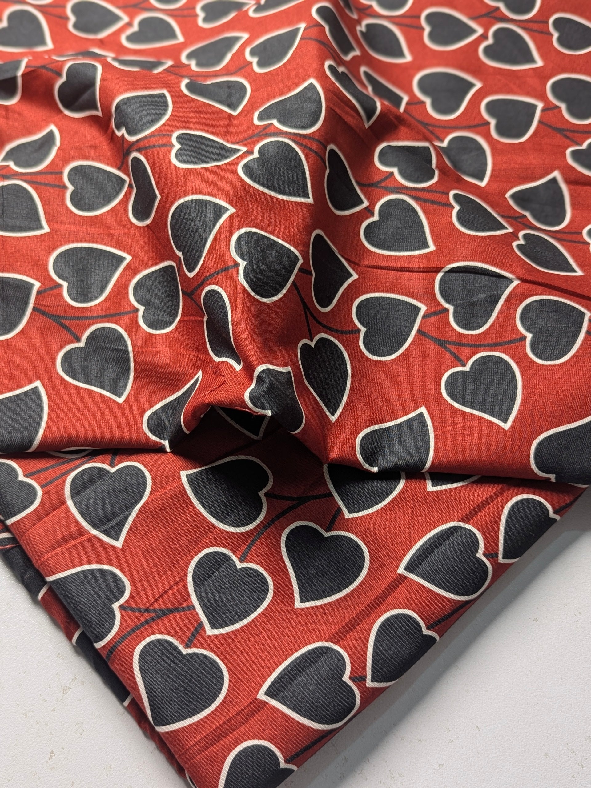 Red fabric with black heart patterns on a white background
