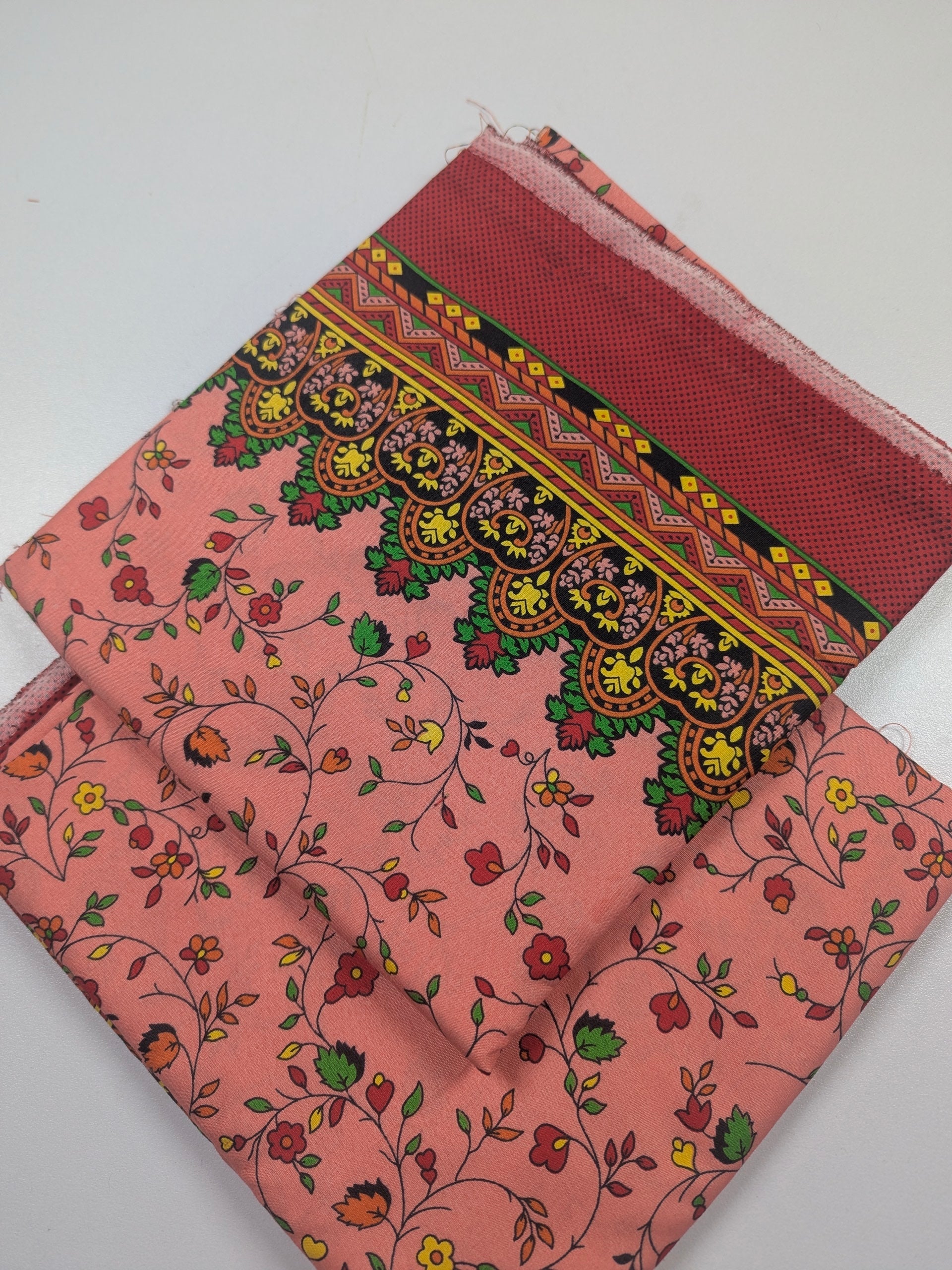 Pink fabric with intricate floral and geometric patterns on a white background