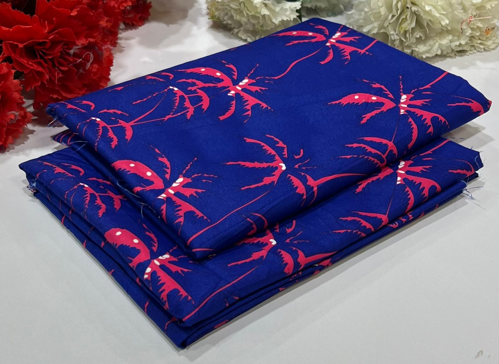 Folded blue fabric with red lobster pattern on a white surface