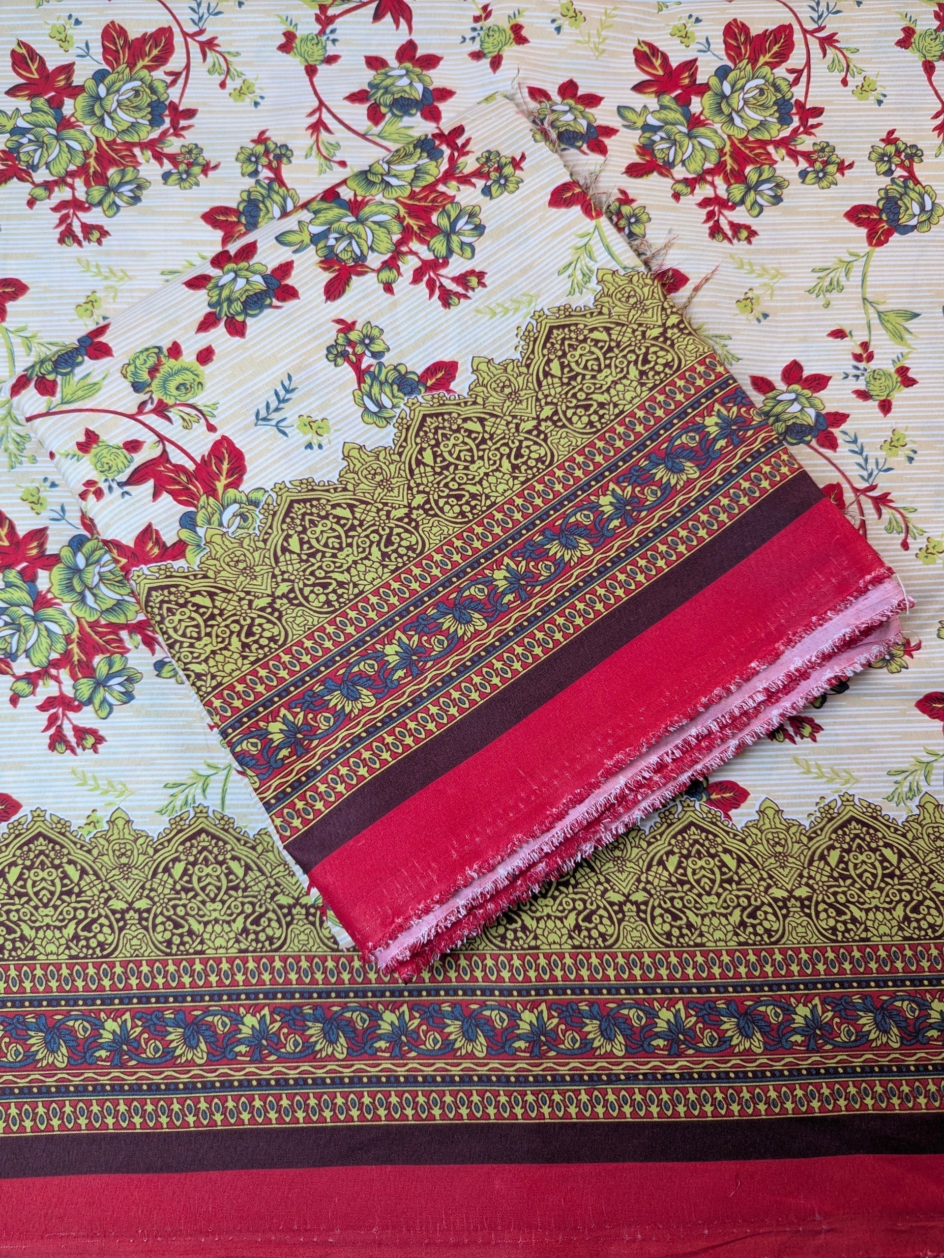 Decorative fabric with intricate patterns and a red border on a floral background