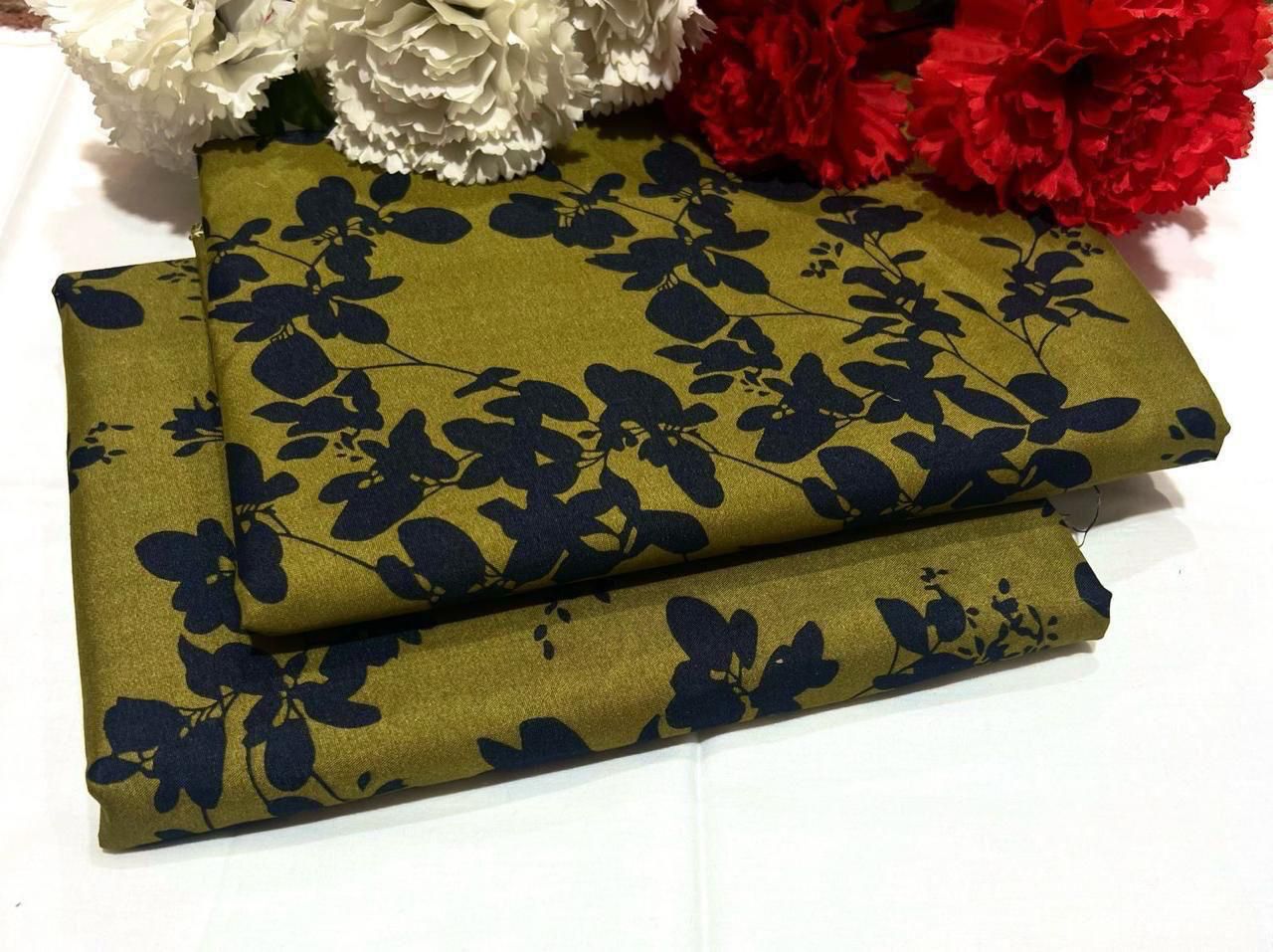 Folded fabric with black floral pattern on a white background with red and white flowers.